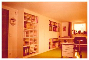 Ein Raum mit eingebauten Regalen und einem Schreibtisch. Das erste Büro von Altena Licht in Weinstadt.
