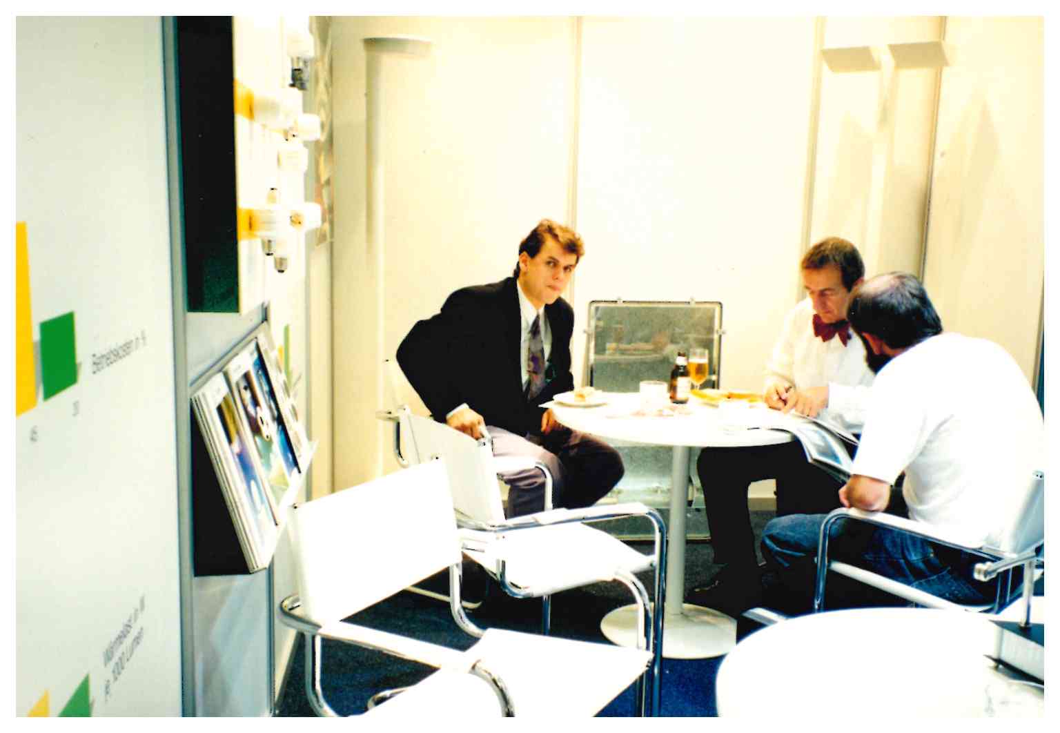 Drei Personen sitzen sich an einem Tisch gegenüber und führen ein Gespräch in einem Büro